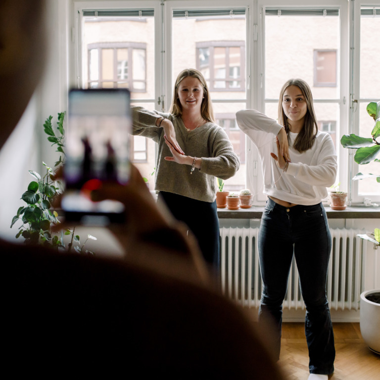 Teenager filmt mit Smartphone seine tanzenden Freundinnen im Wohnzimmer