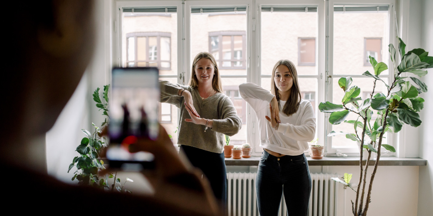Teenager filmt mit smartphone seine tanzenden Freundinnen im Wohnzimmer