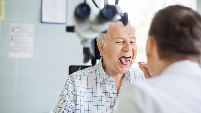 Arzt untersucht die oberen Atemwege eines älteren Patienten