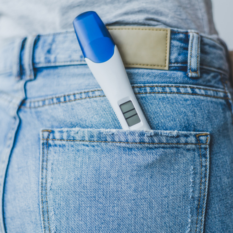 Frau trägt einen Schwangerschaftstest in der rechten Po-Tasche ihrer Jeans