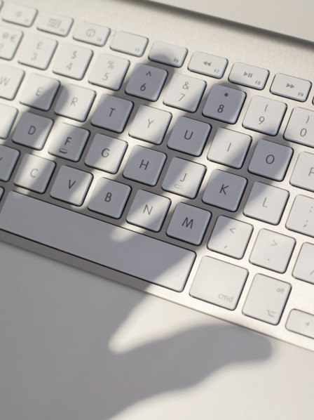 Schatten einer Hand über einer Computertastatur.