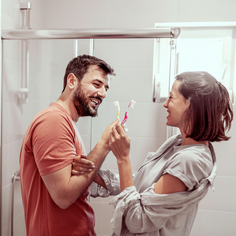 Ein Mann und eine Frau mit ihren Zahnbürsten im Badezimmer.