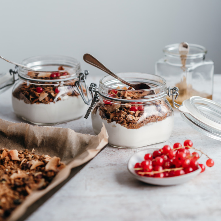 Aus altem Vollkornbrot gebackenes Müsli mit Joghurt und Beeren im Glas.