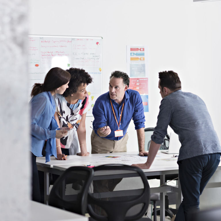 Vier Mitarbeitende besprechen sich im Büro