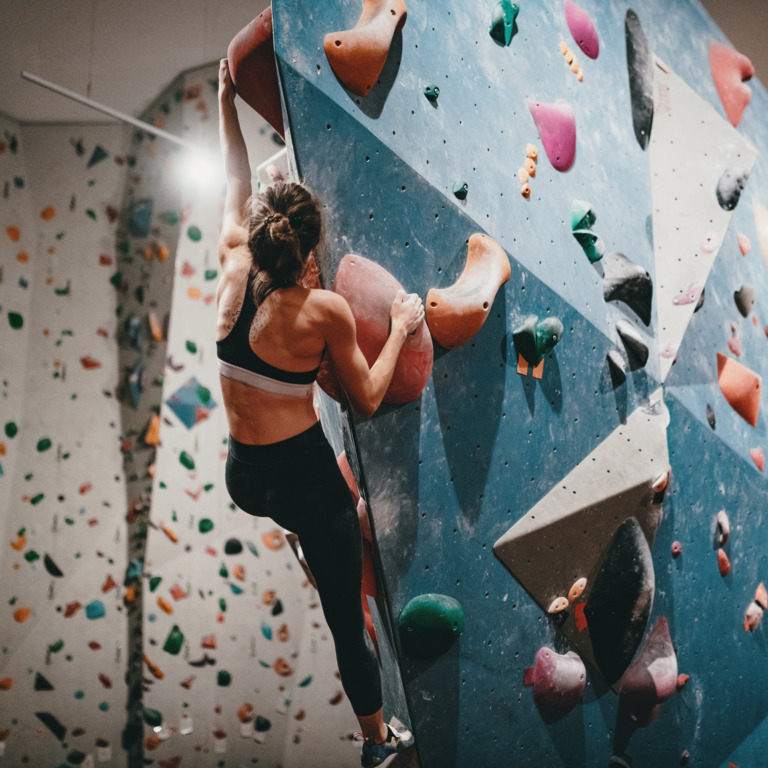Frau klettert in Boulderhalle