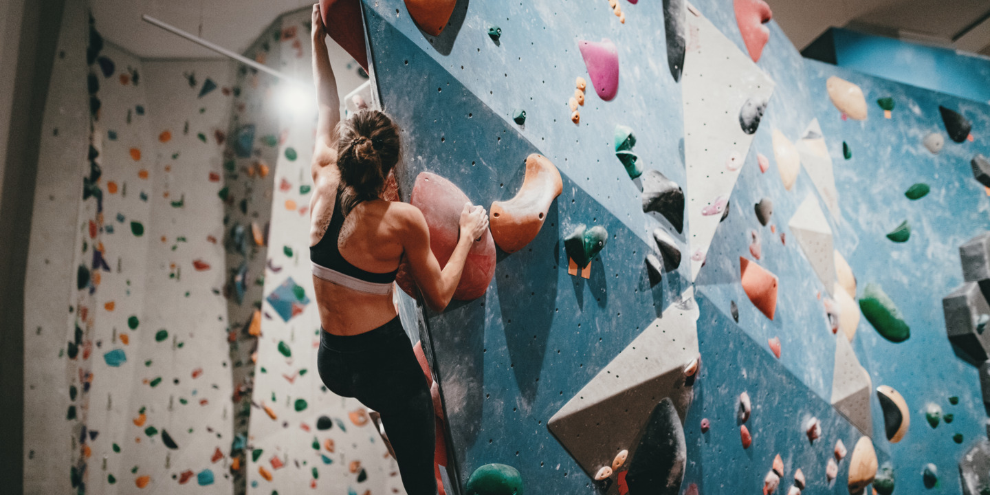 Frau klettert in Boulderhalle