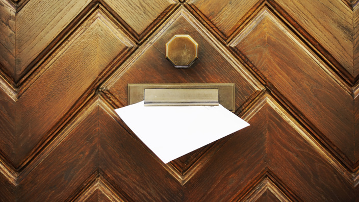Brief hängt im Briefschlitz einer Haustür