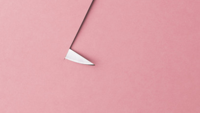 Messer durchschneidet ein rosafarbenes Blatt Papier
