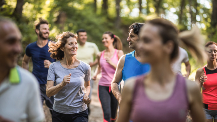 Gruppe von Frauen und Männern beim Joggen durch den Wald