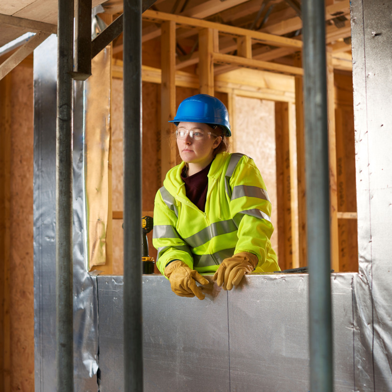 Junge Auszubildende im Handwerk guckt nachdenklich