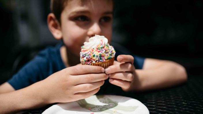Junge hält einen Cupcake in den Händen.