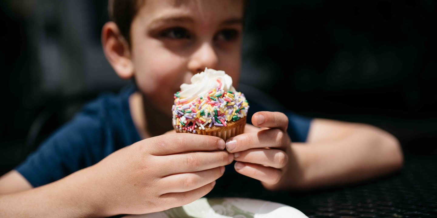 Junge hält einen Cupcake in den Händen.