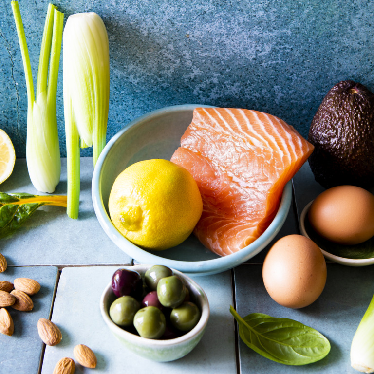 Erlaubte Lebensmittel einer Keto Diät wie Lachs, Avocado, Eier, Oliven, Sellerie und Nüsse