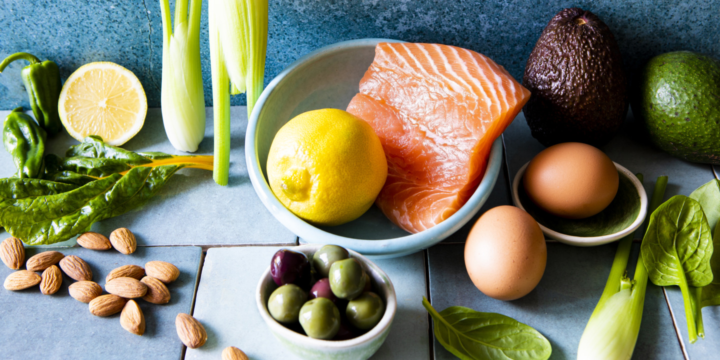 Erlaubte Lebensmittel einer Keto Diät wie Lachs, Avocado, Eier, Oliven, Sellerie und Nüsse