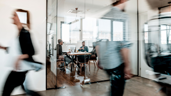 Büro, in dem Mitarbeiter hin und herlaufen