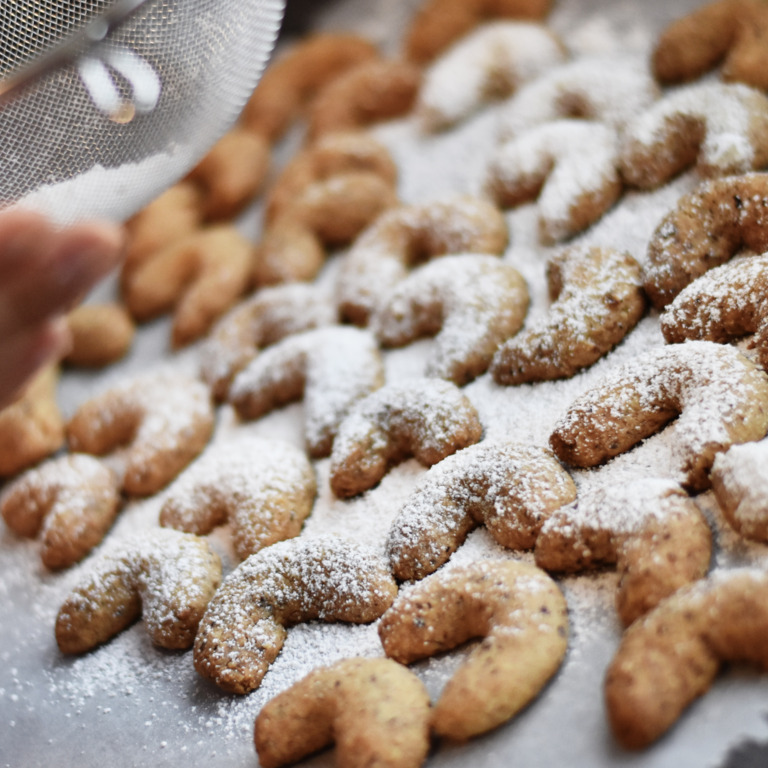 Puderzucker-Sieb über Plätzchen auf einem Backblech