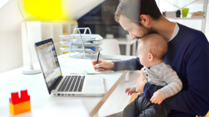 Vater sitzt mit seinem Sohn auf dem Schoß am Laptop