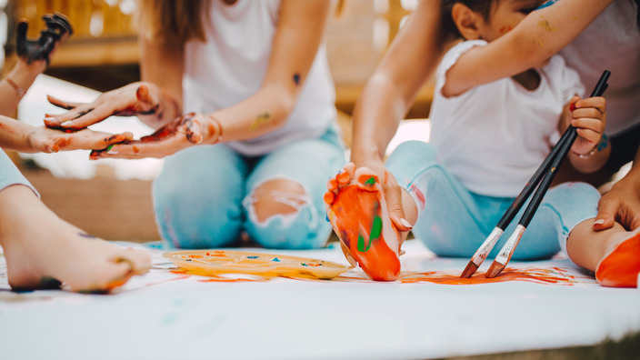 Erzieherinnen einer Kita malen mit Kindern