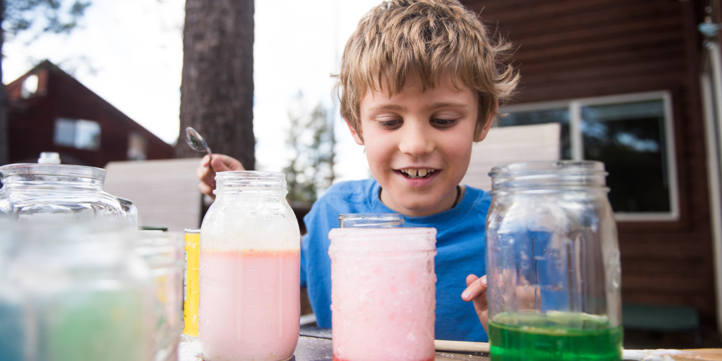 Junge experimentiert im Garten mit Flüssigkeiten