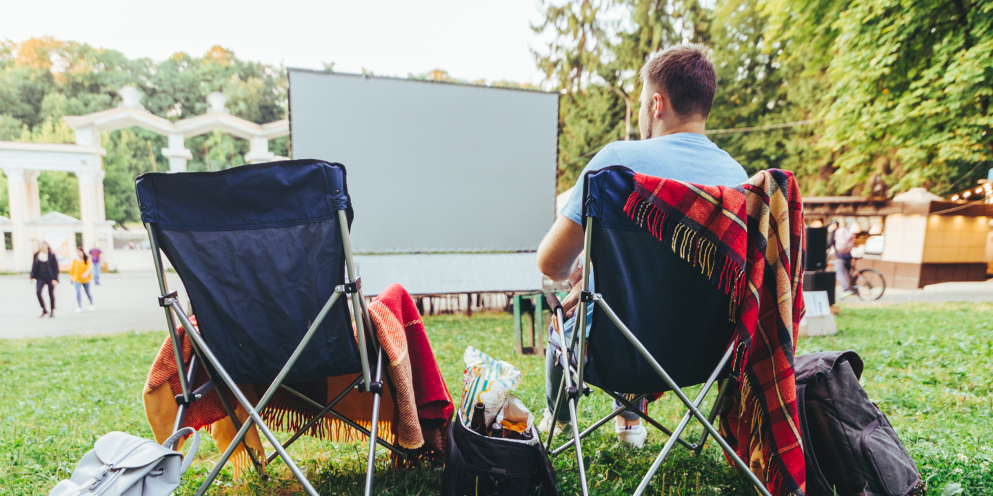 Mann sitzt auf einem Campingstuhl im Open Air Kino