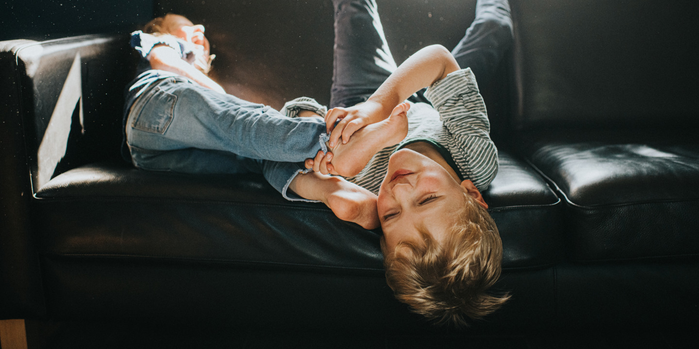 Ist Bewegungsfreude bereits ADHS? Zwei Kinder toben auf dem Sofa.