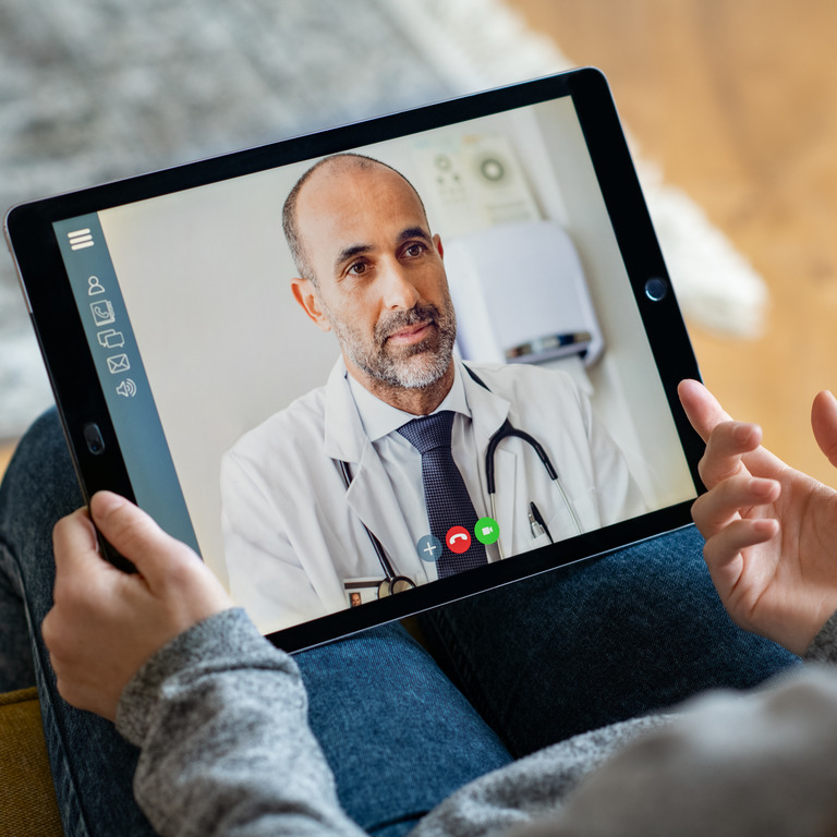 Person spricht zuhause per Video-Chat über ein Tablet mit einem Arzt.