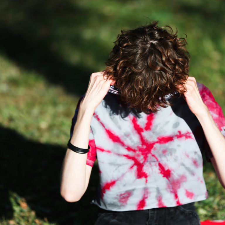 Junge Frau zieht T-Shirt über ihr Gesicht