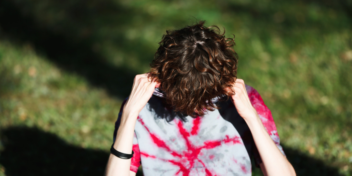 Person mit Burnout vergräbt Gesicht in T-Shirt