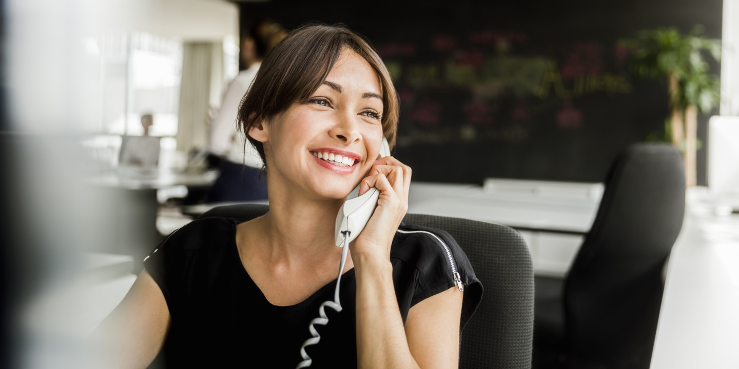 Mitarbeiterin sitzt im Büro und führt ein Kundengespräch am Telefon