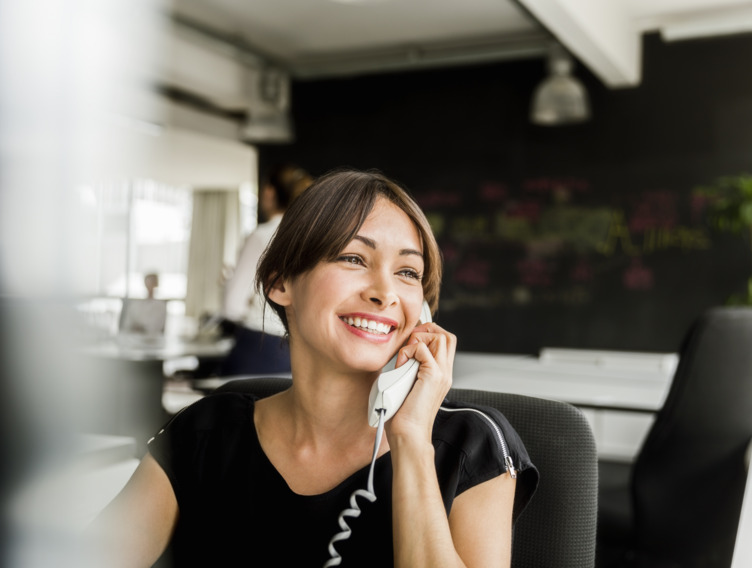 Mitarbeiterin sitzt im Büro und führt ein Kundengespräch am Telefon