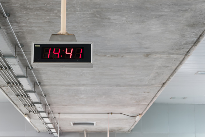 Digitale Uhr hängt von einer Beton-Decke