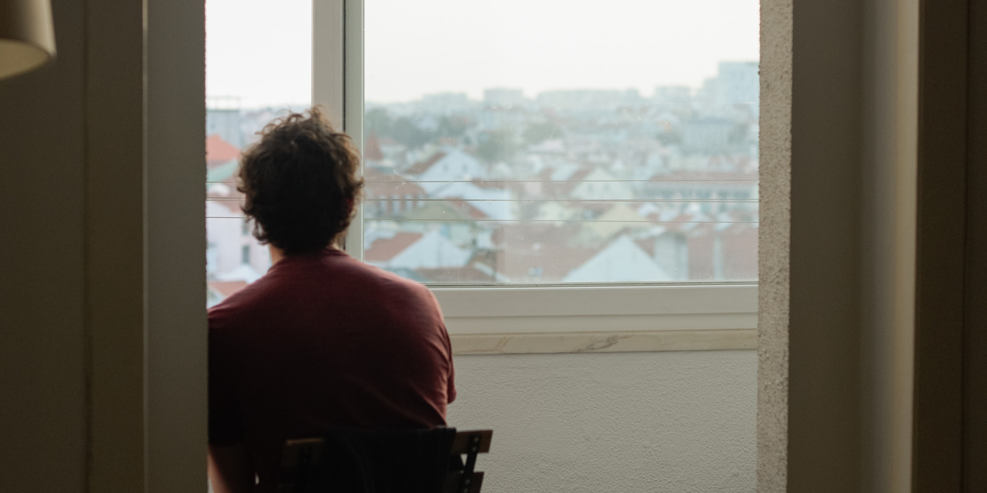 Mann sitzt traurig vor dem Fenster