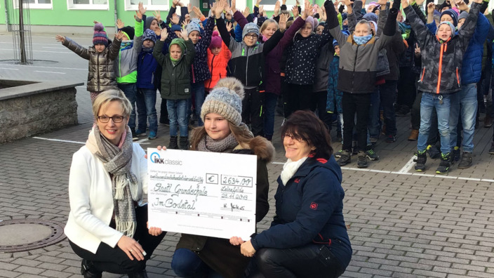 Gruppenbild mit Scheckübergabe vor Grundschule