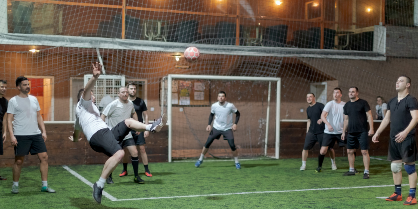 Mehrere Männer spielen Hallenfußball.