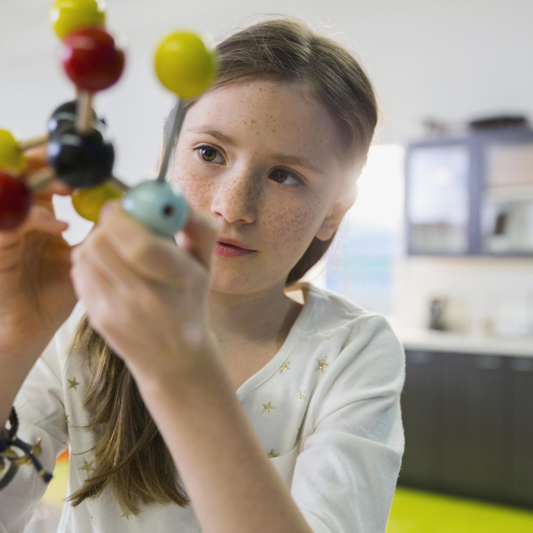 Junge Frau hält ein Modell von einem Molekül in der Hand