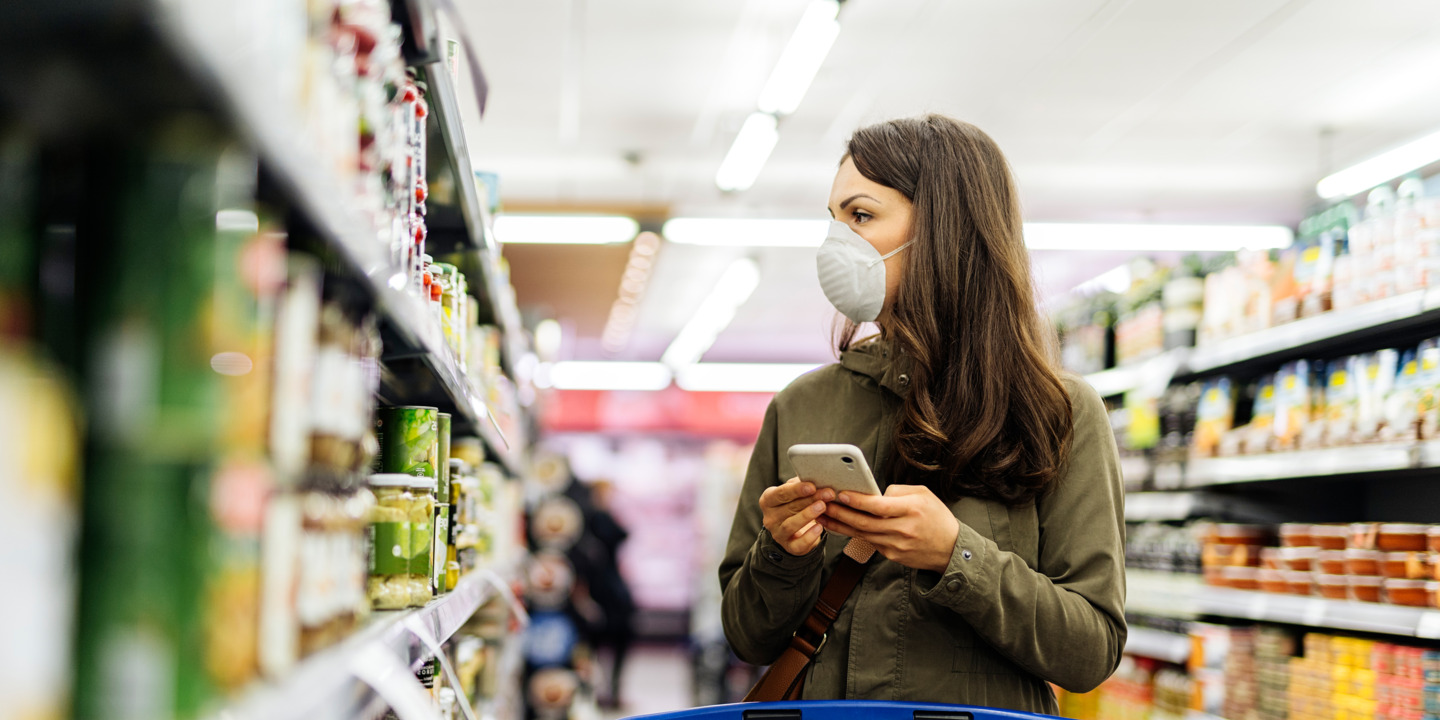 Frau mit Schutzmaske beim Einkaufen im Supermarkt