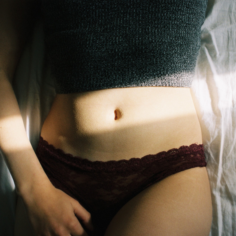 Bauch- und Unterleib-Partie einer im Bett liegenden Frau
