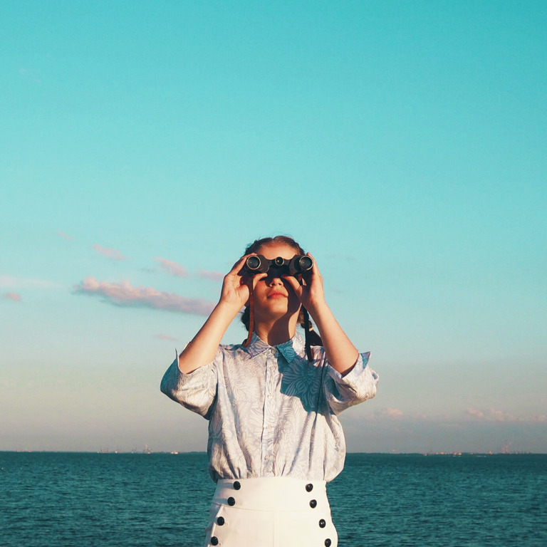 Junge Frau mit Fernglas vor Meer