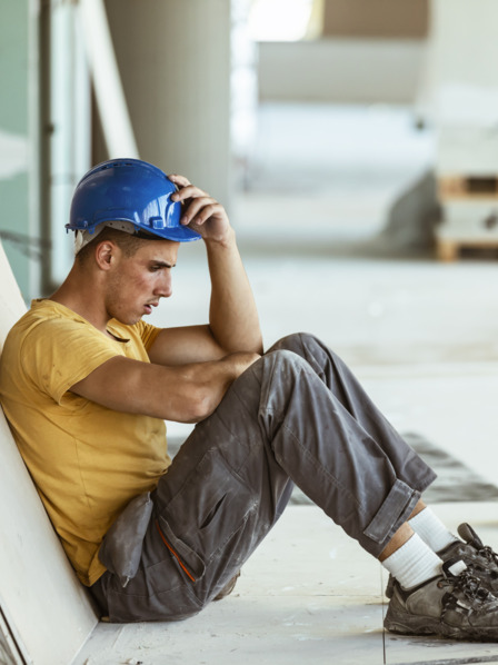 Handwerker mit Burn-out sitzt niedergeschlagen am Boden