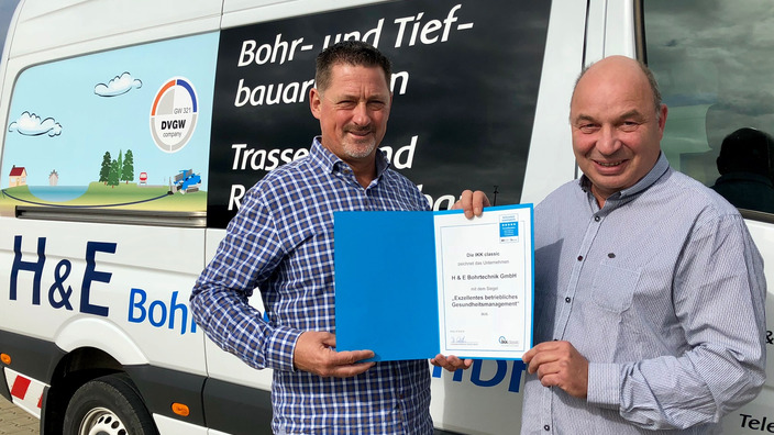 Urkundenübergabe vor dem Firmenwagen der H & E Bohrtechnik