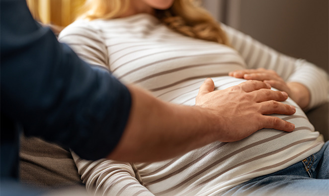Mann legt Hand auf Bauch einer schwangeren Frau