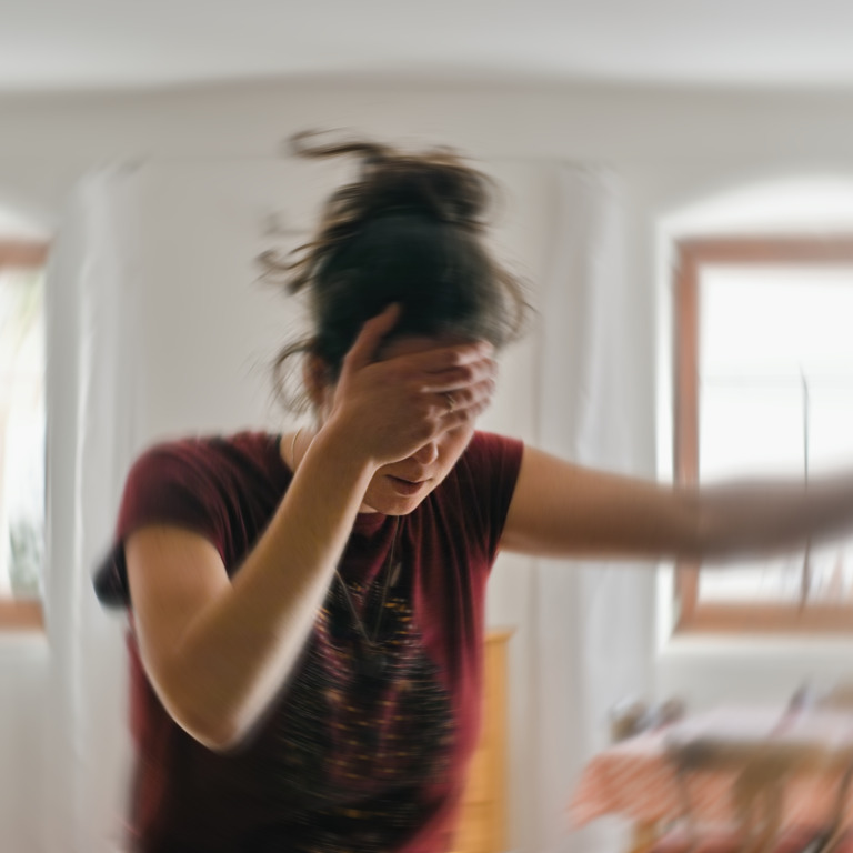 Frau fasst sich an den Kopf, weil ihr schwindelig ist.