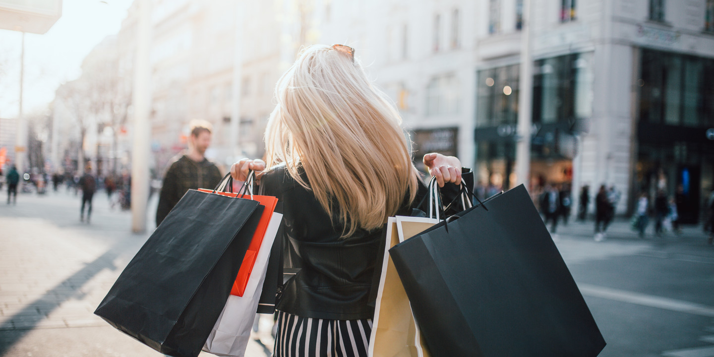 Frau geht mit vollen Shopping-Tüten durch eine Einkaufsmeile