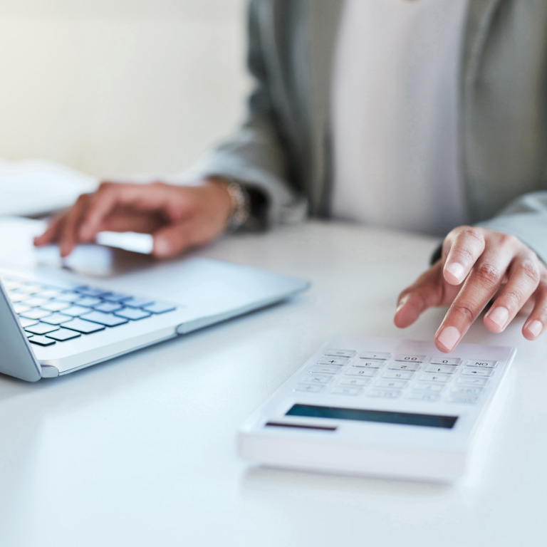 Person tippt auf Taschenrechner und Laptop