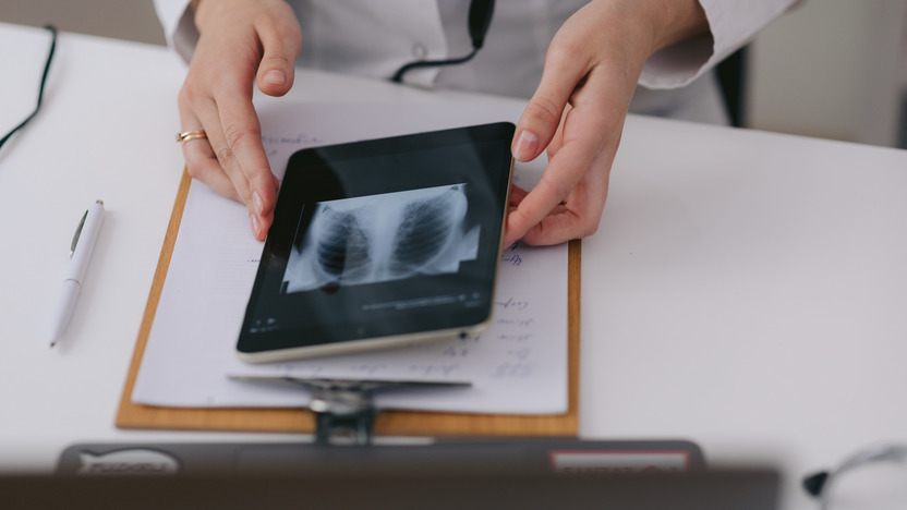 Händepaar hält ein Tablet, auf dem ein Röntgenbild zu sehen ist