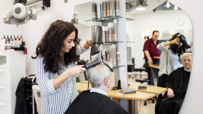 Friseurin schneidet Kundin die Haare