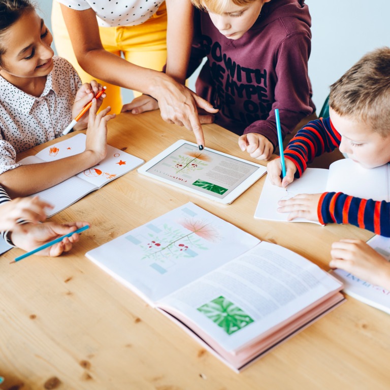 Kinder am Tisch lernen gemeinsam mit Tablet