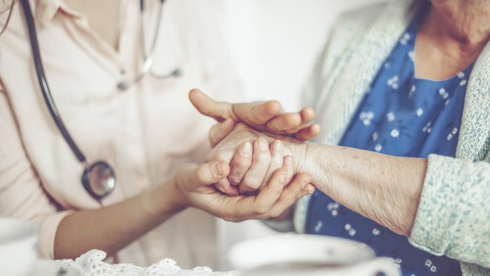 Pflegerin cremt einer Seniorin die Hände ein