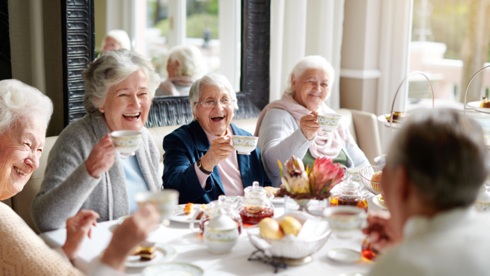 gut gelaunte Gruppe Seniorinnen an einer Kaffeetafel
