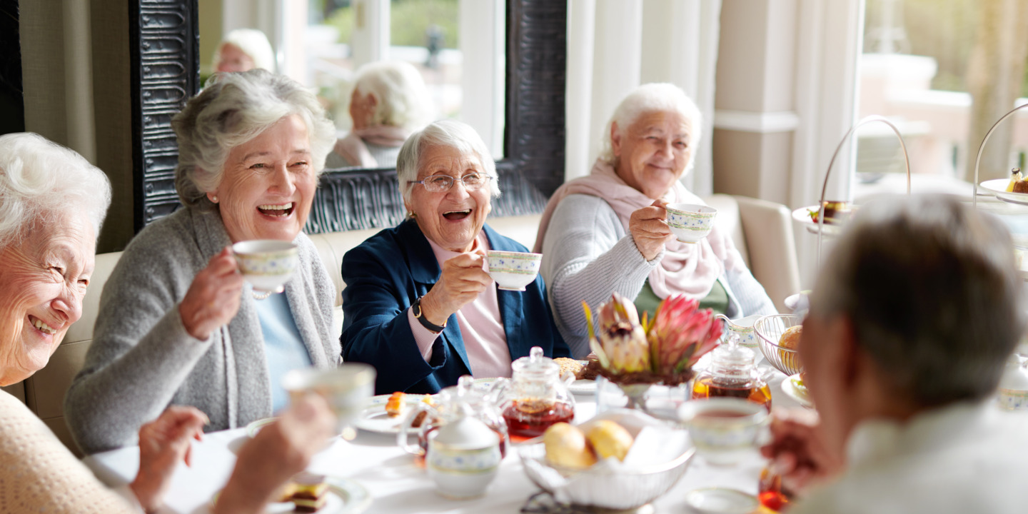 gut gelaunte Gruppe Seniorinnen sitzt an einer Kaffeetafel